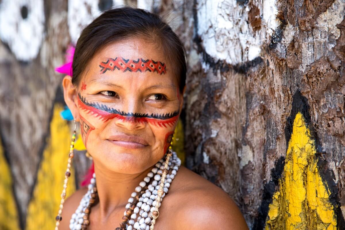 Portrait of an Indigenous woman, her face is painted with traditional art, in Brazil.