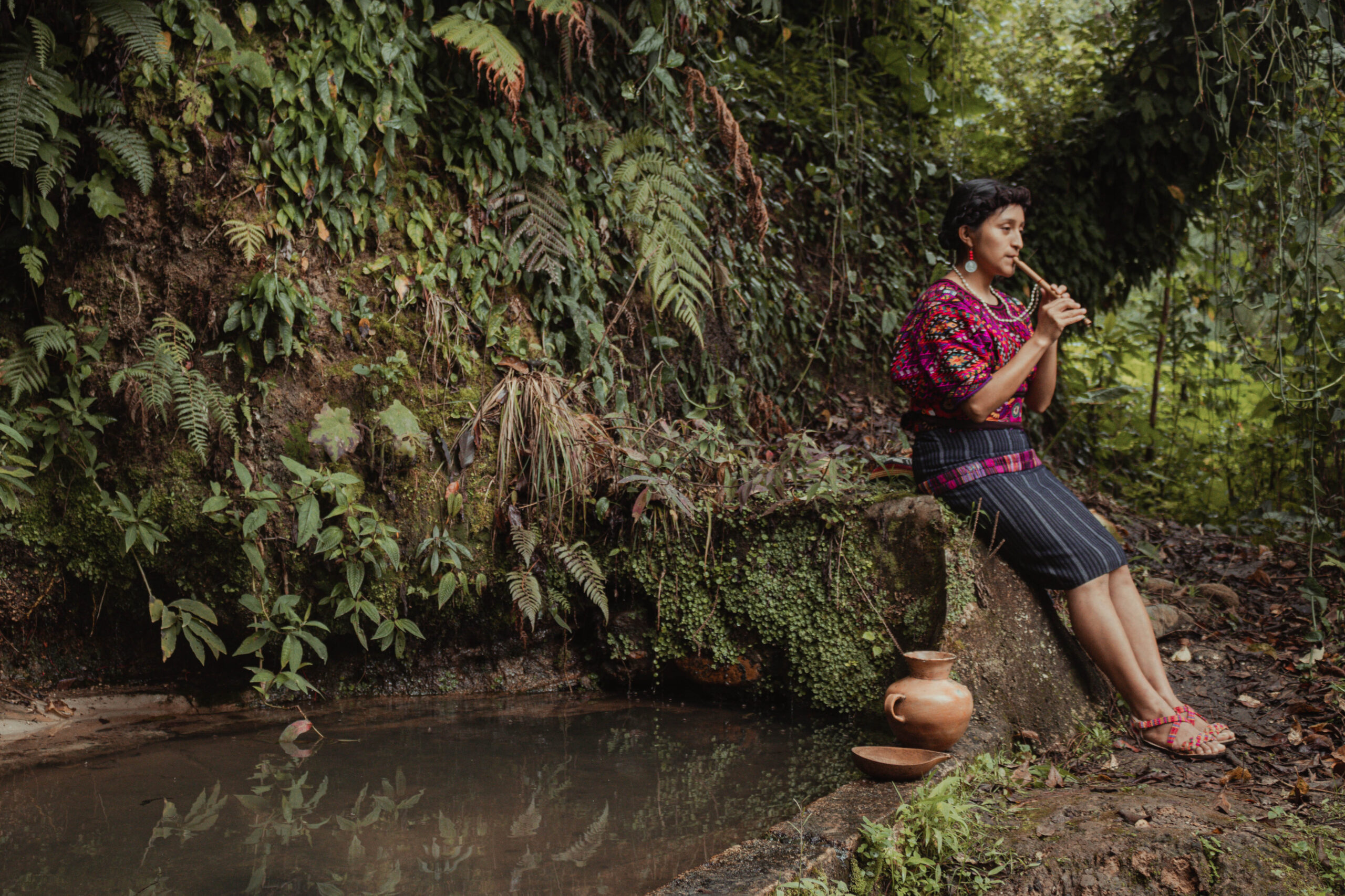 Jovem indígena do Povo Quiché Maya da Guatemala ao lado de uma fonte de água com oferendas em agradecimento à natureza. 
Ganhadores do Concurso de Fotografia “Soluções Inovadoras dos Povos Indígenas”
Nome da foto: Filhos da terra. 
Autor: Alexander Pérez Ventura