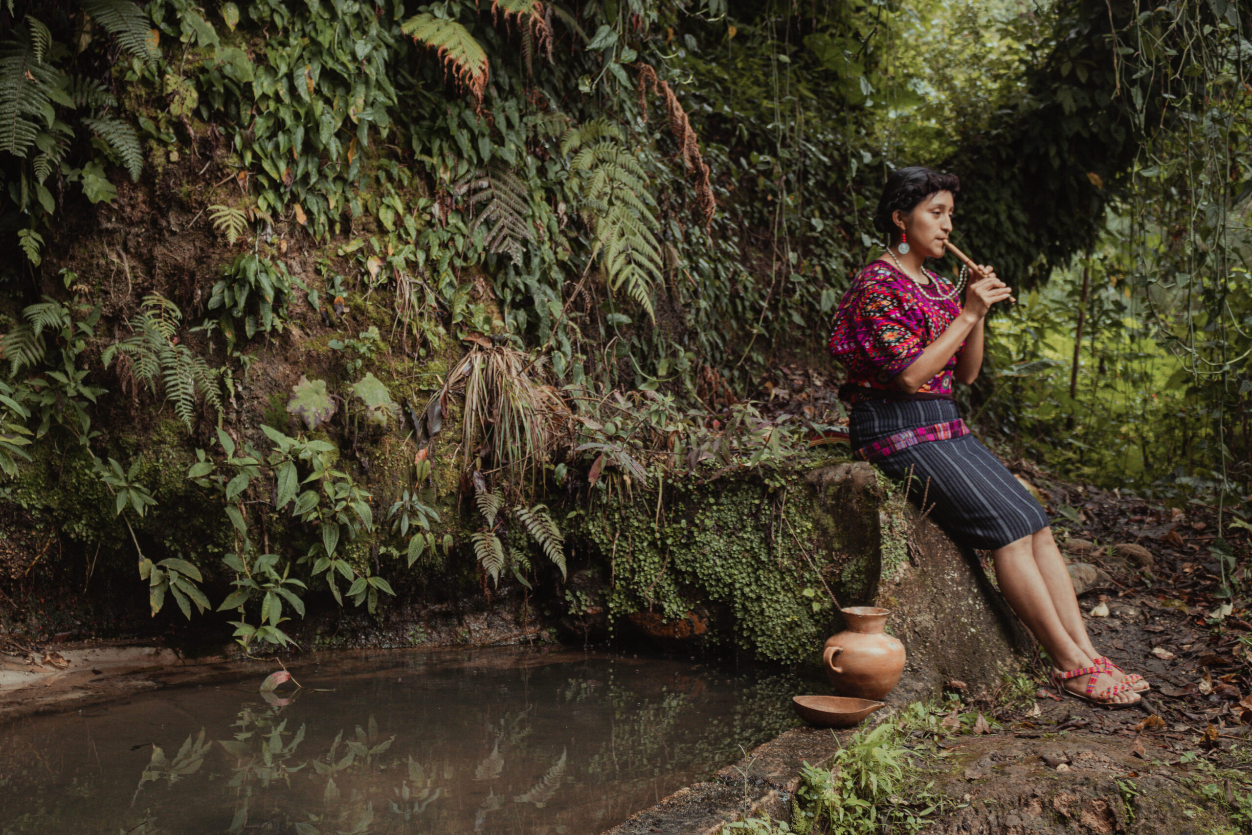 Mujer joven indígena del Pueblo Maya Quiché de Guatemala junto a una fuente de agua con ofrendas en agradecimiento a la naturaleza. 
Ganadores del Concurso de Fotografía “Soluciones Innovadoras de Pueblos Indígenas”
Nombre de la foto: Hijos de la tierra. Autor:  Alexander Pérez Ventura
