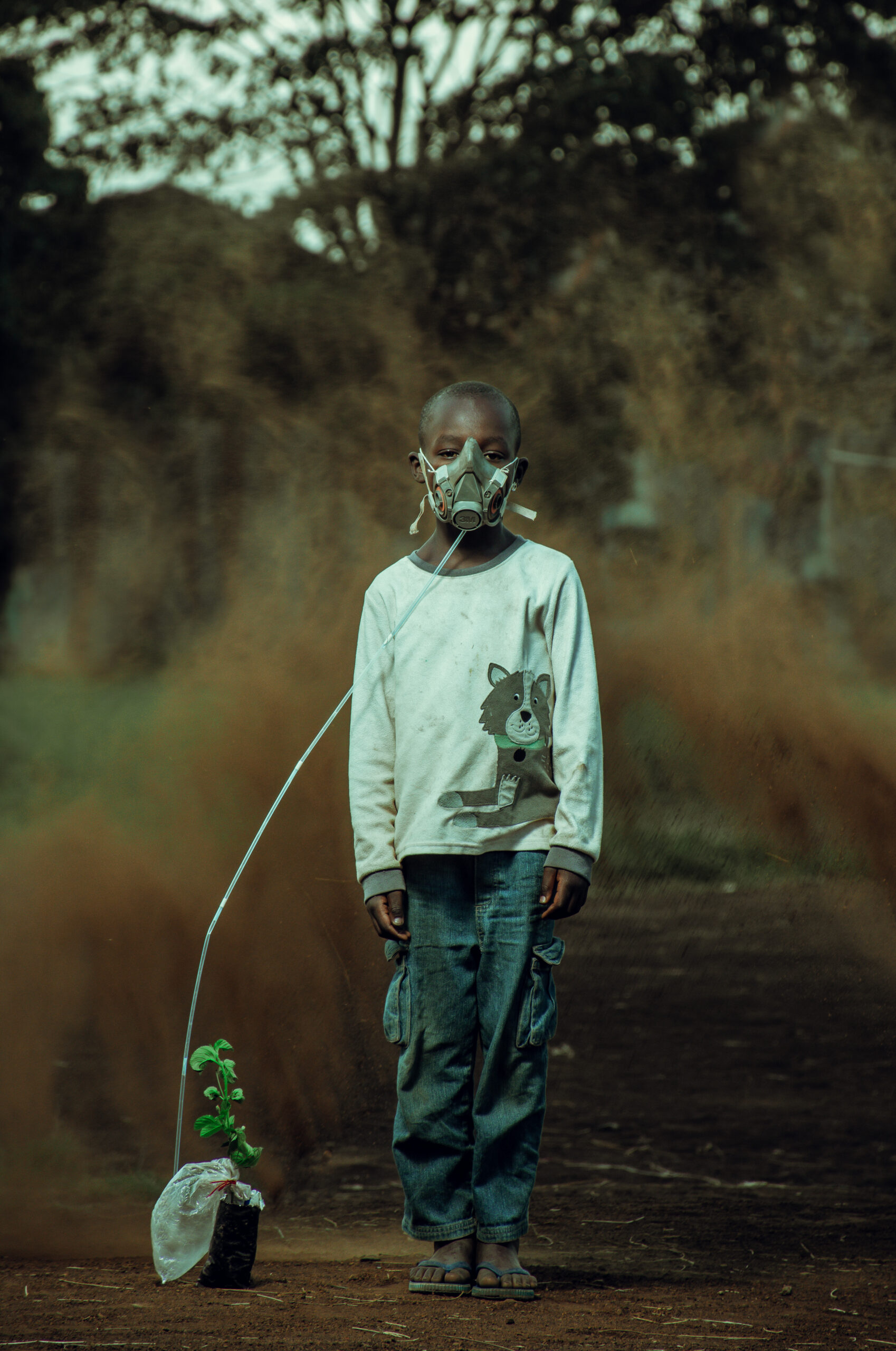 Um menino do povo Luo do Quênia usando uma máscara de oxigênio conectada a uma planta para representar a importância das florestas diante da crise climática. 
Ganhadores do Concurso de Fotografia “Soluções Inovadoras dos Povos Indígenas”
Nome da foto: O último suspiro. Autor: Kevin Ocheng